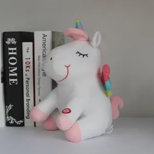 Detalle de un unicornio de peluche blanco con alas de arcoíris y botón interactivo