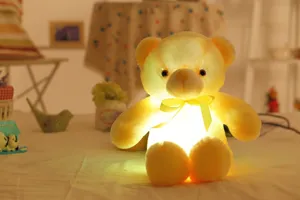 Detail van LED-gloeiende teddybeer knuffel met geel lint in een gezellige warme setting