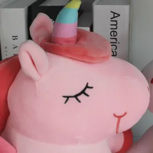 Primer plano detallado de cabeza de unicornio de peluche rosa con cuerno de arco iris suave