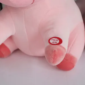 Detalle del botón 'Press Here' en un peluche de unicornio rosa con luz LED