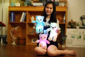 Aziatisch model met drie lichtgevende kleurrijke LED-teddybeer pluche knuffels in huis.