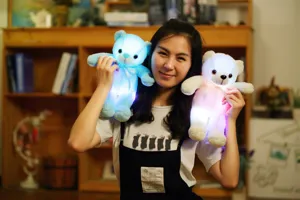 Detailopname van kleurrijke LED-lichtgevende teddyberen vastgehouden door model voor kerstcadeau