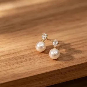 Elegante Nahaufnahme von goldenen Perlenohrringen mit Zirkonia auf einer Holzoberfläche