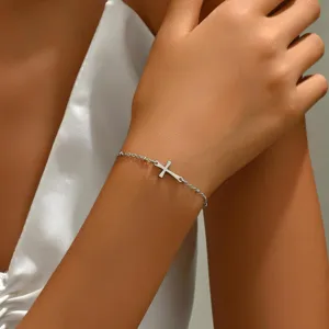Detailansicht des silbernen Kreuzkettenarmbands am Handgelenk einer Frau im Lifestyle-Stil