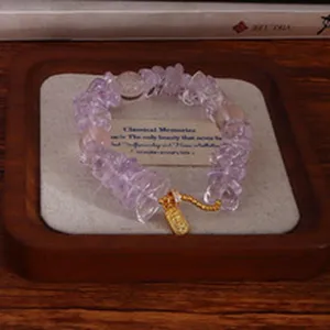 Detailansicht eines Amethyst-Perlenarmbandes mit goldenem Anhänger in einer Schale.