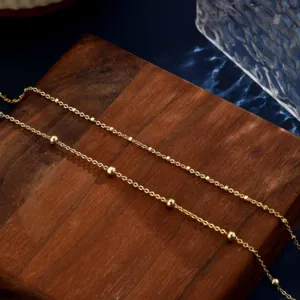 Nahaufnahme eines minimalistischen goldenen Fußkettchens auf Holzgrund