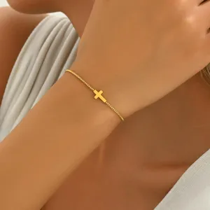 Nahaufnahme eines minimalistischen, vergoldeten, verstellbaren Kreuzarmbands am Handgelenk
