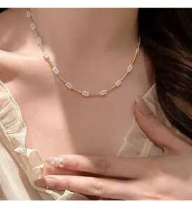 Detailansicht der eleganten Goldkette mit weißen Perlenblumenanhängern im französischen Stil.