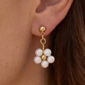 Elegante Nahaufnahme von goldenen Ohrhängern mit einem Perlenblumenanhänger am Ohr