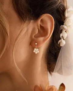 Nahaufnahme eines Braut-Ohrrings mit Perlenblumen, getragen von einem Hochzeitsmodel