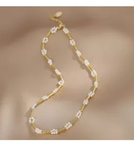 Detailansicht einer eleganten Goldkette mit zarten weißen Perlenblumen-Anhängern.