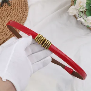 Red patent leather thin belt for women with chic gold metal charm, versatile waist accessory.