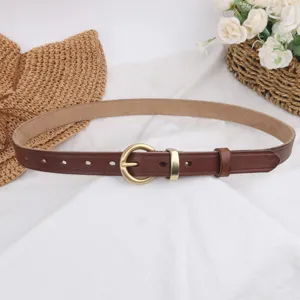 Close-up detail view of women's brown leather belt with elegant gold-tone metal round buckle.