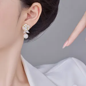 Detailaufnahme eleganter Rosenohrringe mit Zirkon und Perle an einem Modell