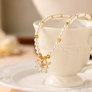 Elegante Perlenhalskette mit Blumenanhänger an einer weißen Teetasse aus Porzellan