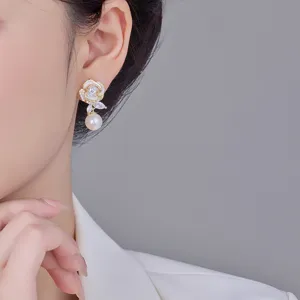 Elegante Blumen-Ohrhänger mit weißer Emaille und Perle am Ohr eines asiatischen Models