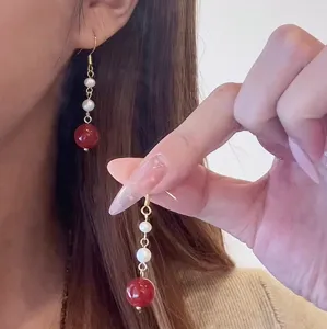 Detailansicht eleganter langer Perlenohrringe mit weißen Perlen und roter Achatperle.