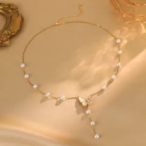 Nahaufnahme einer eleganten Goldkette mit Schmetterlingsanhänger, Perlen und Zirkonia.