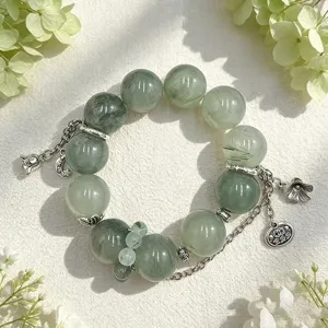 Detailansicht eines Armbands aus grünem Rutilquarz mit silbernen Blumenanhängern.