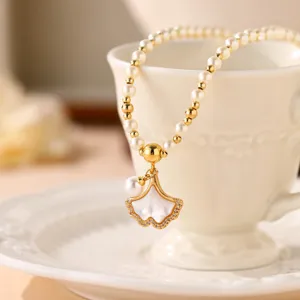 Elegante Perlenkette mit Ginkgoblatt-Anhänger an einer weißen Tasse im Detail