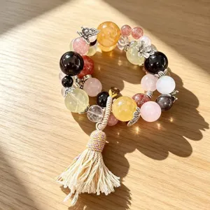 Nahaufnahme eines bunten Kristallperlenarmbands mit silbernen Schmetterlingen und Quaste.