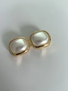 Closeup view of gold-rimmed square pearl belt buckle, elegant geometric decor accessory.
