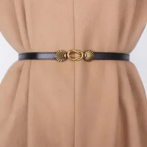 Detailed view of a slim black leather belt with a vintage bronze shell buckle, elegant accessory.