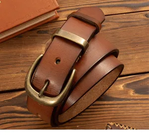 Detailed view of men's genuine leather belt with brass buckle on rustic wooden background.