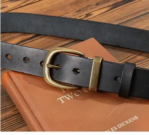 Close-up detail of vintage genuine leather men belt with solid brass pin buckle on retro book.