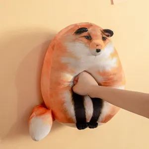 Soft round fox plush pillow toy being squeezed to show its high elasticity.