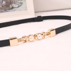 Detail view of black thin leather belt featuring gold metal buckle and elegant faux pearl decor.