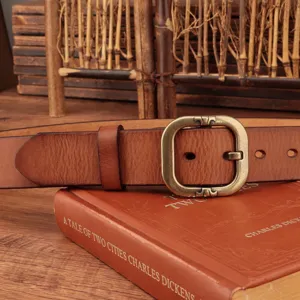Detailed view of vintage genuine leather belt with retro metal buckle on classic book prop.