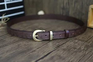 Λεπτομερής κοντινή όψη γυναικείας δερμάτινης ζώνης με μεταλλική αγκράφα πέταλου σε ρετρό στυλ.