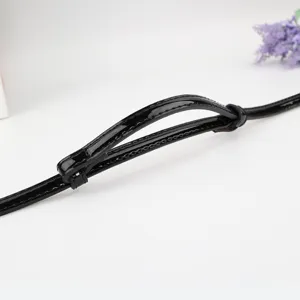 Nahaufnahme Detailansicht des schmalen schwarzen Lackleder Gürtelriemens mit feinen Nähten.