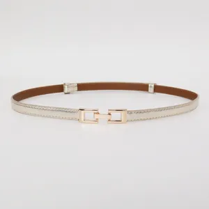 Detail view of a slim metallic gold leather women's belt with stylish interlocking buckle.