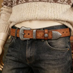 Retro leather belt detail showing ornate carved metal buckle, tip, and embossed cowhide pattern.