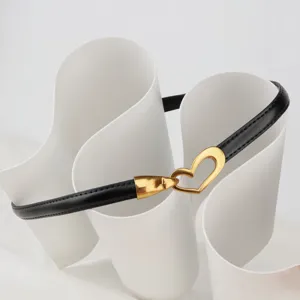 Detailed close-up of a stylish thin black leather belt with an elegant gold heart-shaped buckle.