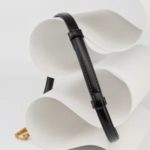 Women's thin black leather dress belt detail showing premium texture and gold buckle design.