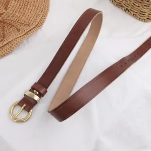 Close-up view of brown genuine leather skinny belt with elegant golden metal buckle detail.