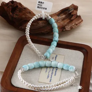 Detailansicht von Armbändern aus Larimar und Süßwasserperlen auf einem Holzdisplay