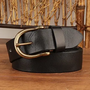 Close-up detail of black leather belt with vintage brass horseshoe buckle for casual wear style.