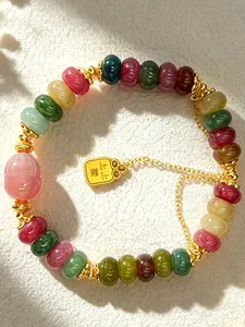 Detailed view of a multi-color natural crystal beaded bracelet with a gold luck charm.