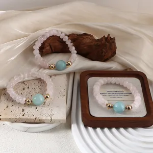 Close-up of three pink quartz beaded bracelets with aquamarine centerpieces on elegant props
