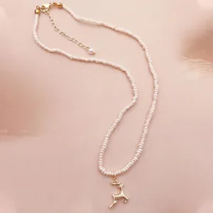 Detailansicht einer eleganten Süßwasserperlenkette mit einem goldfarbenen Hirsch-Anhänger