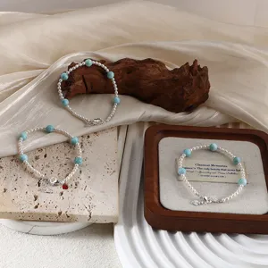 Detail of elegant pearl and aquamarine bracelets with silver charms on rustic props.