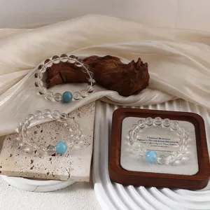Natural aquamarine and white crystal beaded bracelets displayed on elegant wooden props