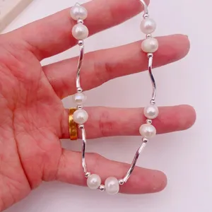 Nahaufnahme einer Süßwasserperlenkette mit eleganten geschwungenen Silberröhren