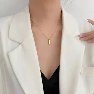 Close-up of a minimalist gold-toned titanium steel bar necklace on a model