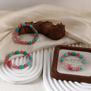 Detail view of pink and teal natural stone bracelets on elegant wooden and silk display