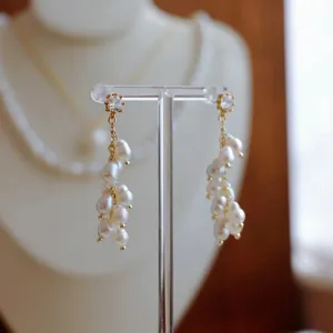 Makroansicht langer goldener Quastenohrringe mit weißen Barockperlen-Clustern